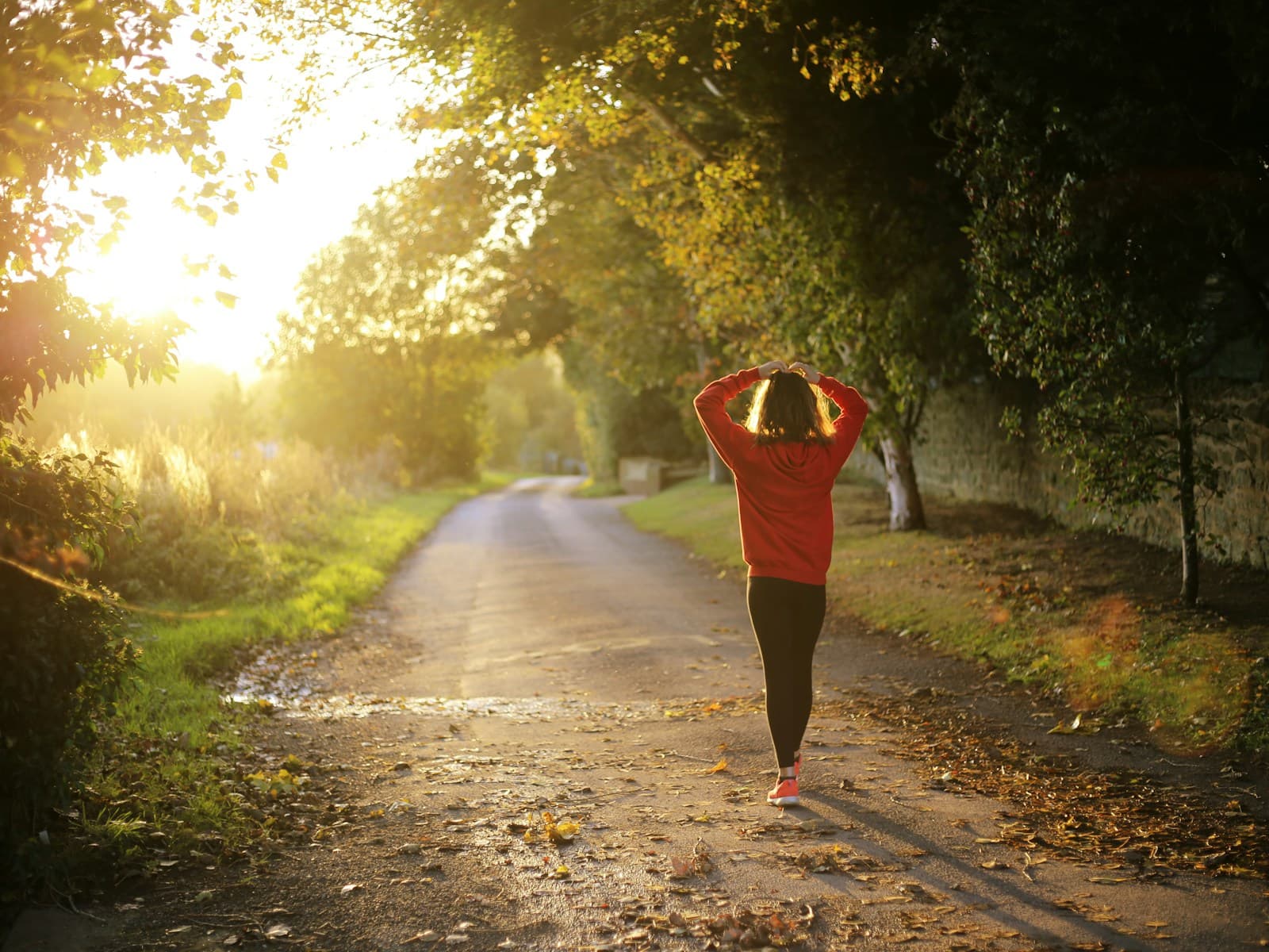 A person walking along a quiet path in warm morning light.